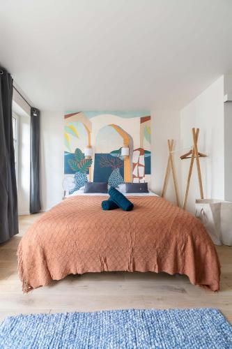 a bedroom with a large bed with a orange blanket at Résidence Aristide Briand - Appartements en Centre Ville in Vichy