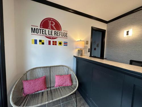 a room with a counter and a chair with pink pillows at Motel Le Refuge in Sherbrooke