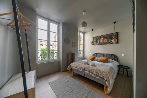a bedroom with a bed and two windows at Résidence Aristide Briand - Appartements en Centre Ville in Vichy