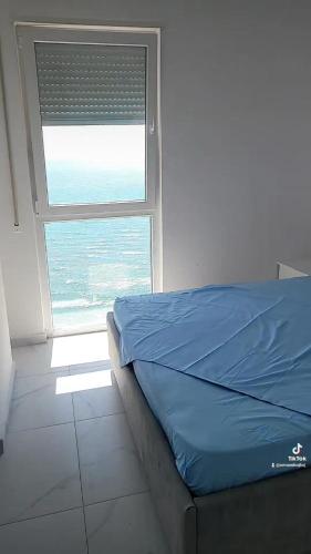 a bedroom with a blue bed and a window at Amfora apartments in Lezhë