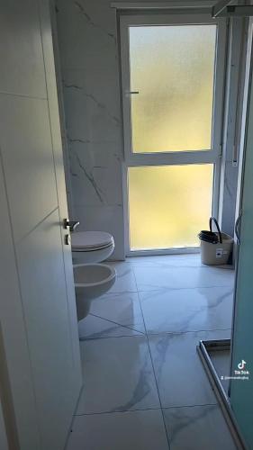 a bathroom with a toilet and a window at Amfora apartments in Lezhë