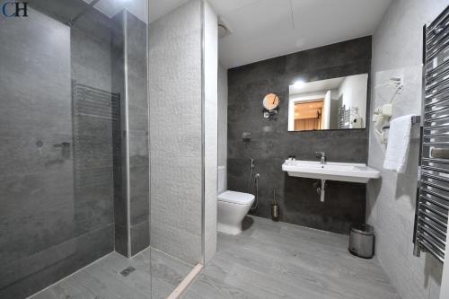 a bathroom with a shower and a toilet and a sink at Hotel Chaker in Batna