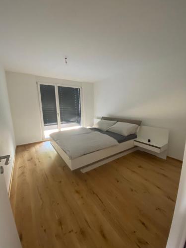 a white bedroom with a bed and a wooden floor at Triesenberg in Triesenberg