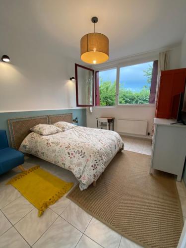 een slaapkamer met een bed en een groot raam bij Gîte épicéa indépendant avec jardin in Méry-sur-Oise