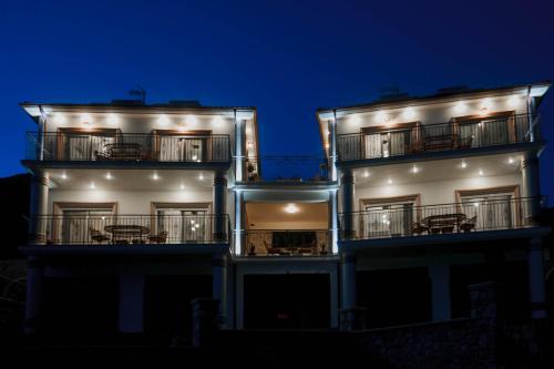 a two story building with balconies and tables at Natura Luxury Suites Parga in Parga