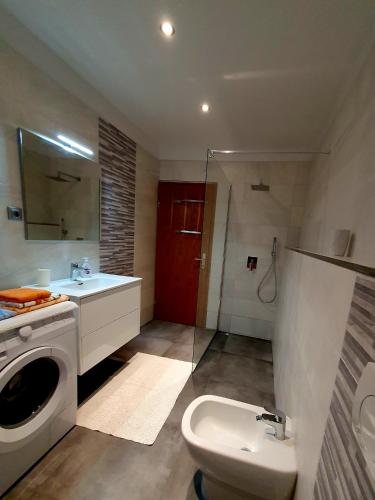 a bathroom with a washing machine and a sink at ForRest Apartment in Portorož