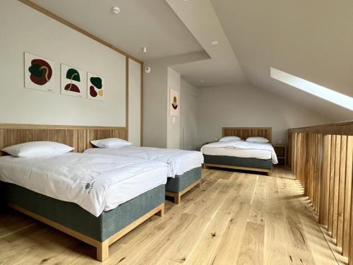 two beds in a room with wooden floors at Willa Leśna in Ustka