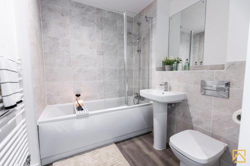 ein Badezimmer mit einem Waschbecken, einer Badewanne und einem WC in der Unterkunft Outstanding 5 Bedroom Townhouse, Canal Views By Valore Property Services in Milton Keynes