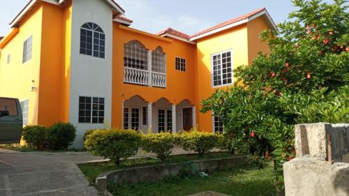an orange and white house with a tree at Rio View Apartments in Ocho Rios