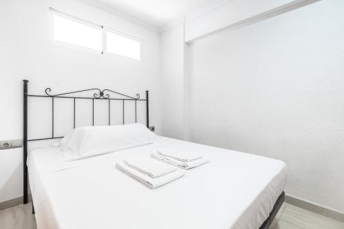 um quarto branco com uma cama com duas toalhas em Carabelas III 1-3 Apartment Levante Beach em Benidorm