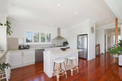 a kitchen with white cabinets and a kitchen island with stools at Beach Retreat Casuarina Near Osteria Weddings in Casuarina