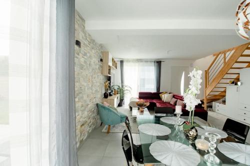 a living room with a glass table with umbrellas on it at Maison de Vacances Familiale à 15 minutes de Saint-Malo in Miniac-Morvan