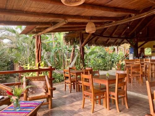 Un restaurante con mesas y sillas de madera en un patio. en La Buena Vida Hotel, en Ayampe