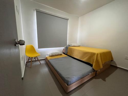 Un dormitorio con una cama y una silla amarilla. en BONITO DEPA ! Cerritos a 2 Cuadras de PLAYA, en La Florida