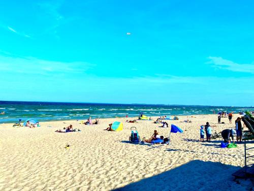 a group of people on a beach with the ocean at Modernes Apartment an Timmendorfer Promenade, 1. Reihe in Timmendorfer Strand