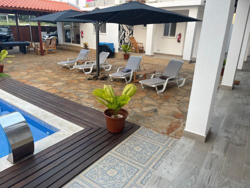 a patio with chairs and an umbrella next to a pool at Hotel Kenito in São Tomé