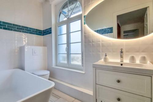 une salle de bain blanche avec un lavabo et un miroir dans l'établissement ROYAN - Villa La Cigale - 7 chambres / 16 couchages, à Royan