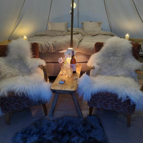 Viksdalen的住宿－Flatheim Glamping，一间设有两把白色毛绒椅子和一张桌子及一张床的房间
