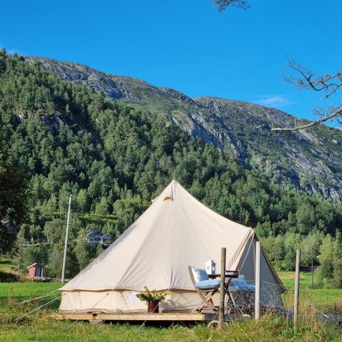 a tent with a table and a chair in a field at Flatheim Glamping in Viksdalen