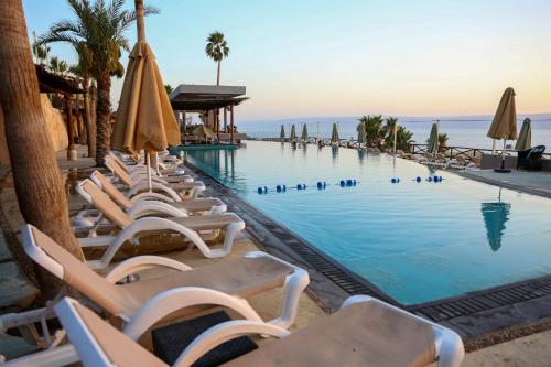 O Beach Hotel & Resort في السويمة: مسبح مع كراسي الصالة والمظلات