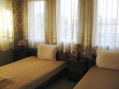 a bedroom with two beds and a window with curtains at Elefterova kashta in Arbanasi