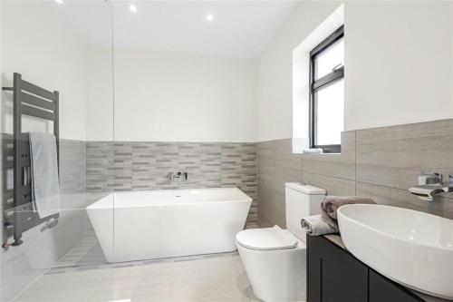 a bathroom with a tub and a toilet and a sink at 田园居 in Orpington