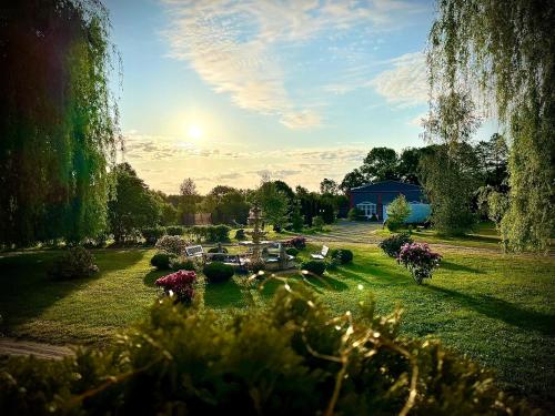 a garden with flowers and a blue building in the background at Agroturystyka Hotel Noclegi Pałac Camping in Wałcz