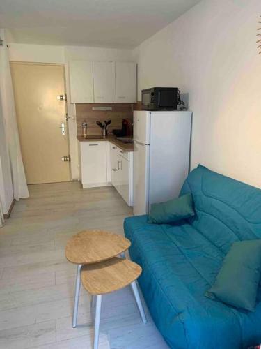 un salon avec un canapé bleu et une table dans l'établissement Appartement f2 bord de mer, à Frontignan