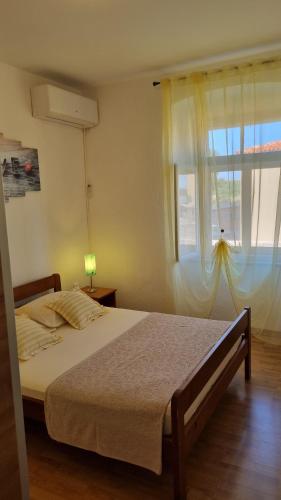 a bedroom with a large bed with a window at Apartman Mila in Belej