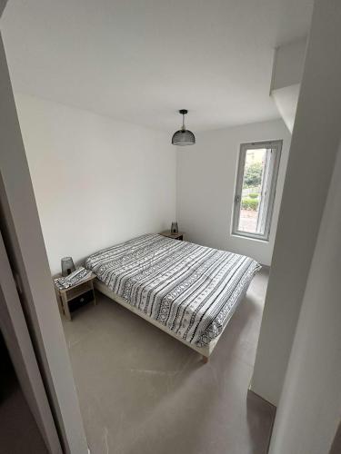 um quarto branco com uma cama e uma janela em Appartement cap agde port 4 couchage em Cap d'Agde