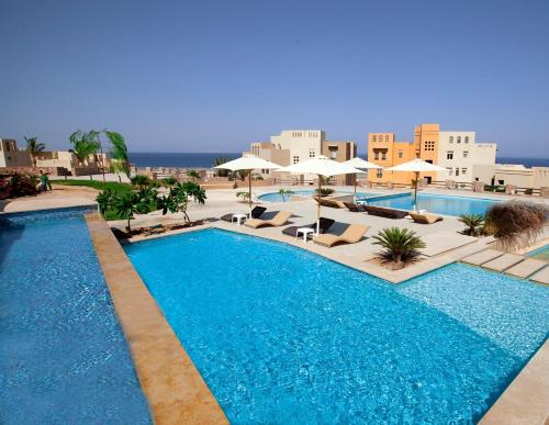 a pool with chairs and umbrellas in a resort at Azzurra Sahl Hasheesh in Hurghada