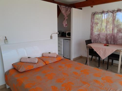 Bungalow Miwa في بوناويا: غرفة نوم بسرير وطاولة ومطبخ