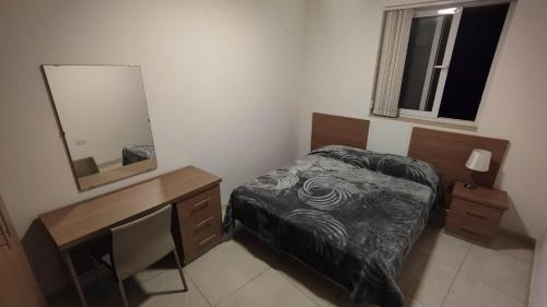 1 dormitorio con cama, escritorio y espejo en Private Room in a Big aparment, en Msida