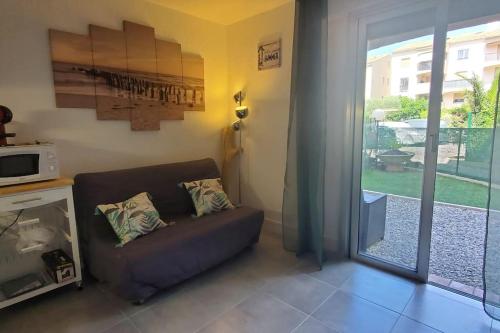 a living room with a couch and a sliding glass door at Studio proche plage tout à pied in Fréjus