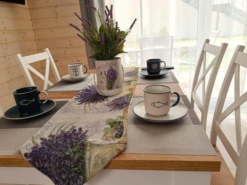 Una mesa con tres tazas de café y flores encima. en Lawendowe Domki i Apartamenty w Pobierowie, en Pobierowo