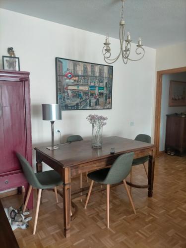 a dining room table with green chairs and a lamp at FEMALE ONLY Pinar de Chamartin room in Madrid