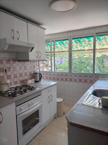 a kitchen with a stove and a sink and windows at FEMALE ONLY Pinar de Chamartin room in Madrid