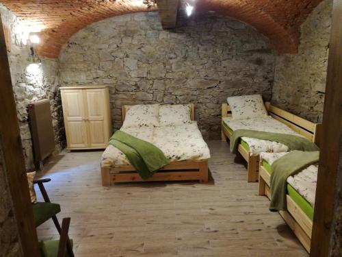 Cette chambre est dotée de 3 lits et d'un mur en pierre. dans l'établissement Niezapominajka, à Kletno