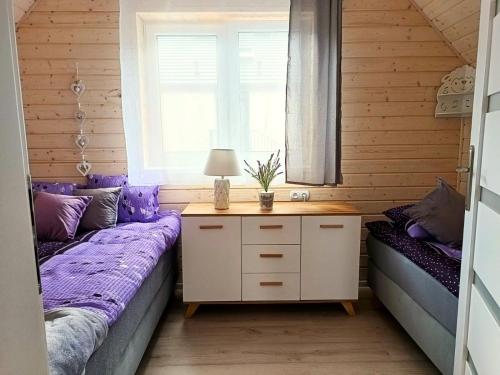 1 dormitorio con camas de color púrpura y ventana en Lawendowe Domki i Apartamenty w Pobierowie, en Pobierowo
