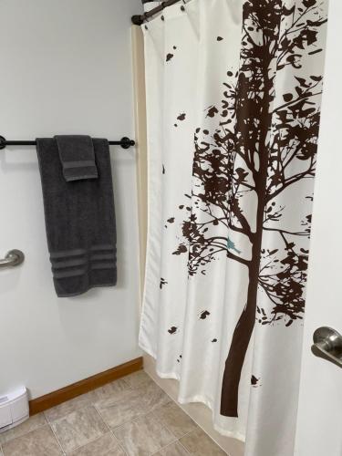 a bathroom with a shower curtain with a tree and birds at Falls Edge Farm Cottage in Benton