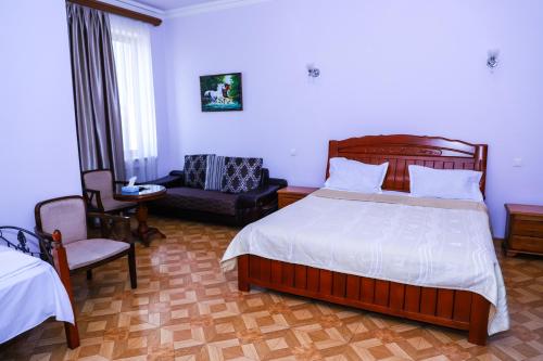 a bedroom with a bed and a chair and a couch at SD David Hotel in Yerevan