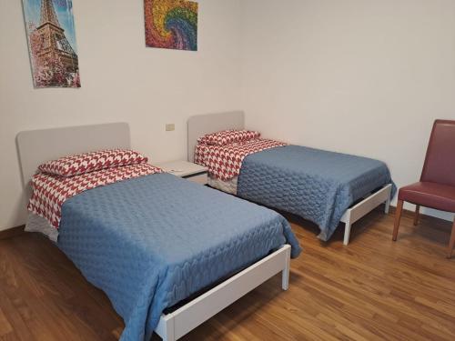 Habitación con 2 camas y silla roja. en Il posto Giusto, en Pieve di Soligo