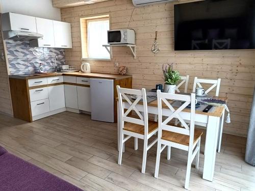 a kitchen with a table and chairs in a room at Lawendowe Domki i Apartamenty w Pobierowie in Pobierowo