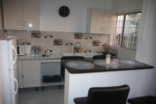 a kitchen with white cabinets and a black counter top at Appartement à 5 min de la plage in Bouéni