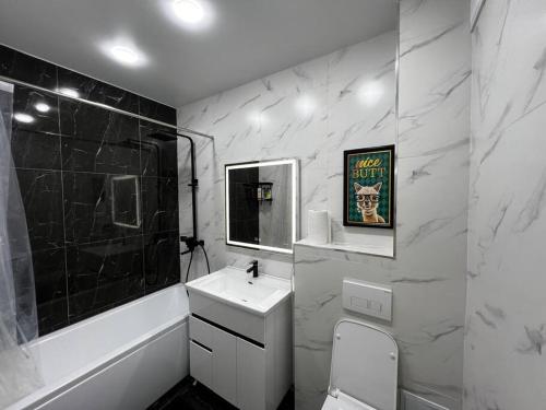 a black and white bathroom with a sink and a mirror at Entire Apartment in Central Nukus in Nukus