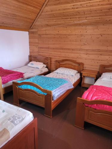 a room with three beds in a wooden cabin at Apartamente plazhi in Sarandë