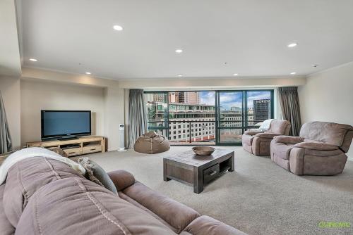 a living room with a couch and a flat screen tv at QV Stays Front Stage City Lights in Auckland