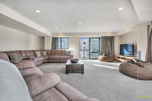 a large living room with a couch and a tv at QV Stays Front Stage City Lights in Auckland