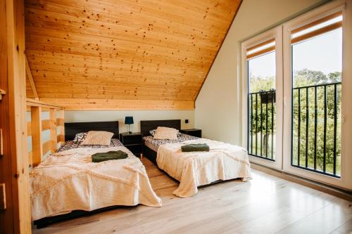 two beds in a room with wooden ceilings and windows at Domki Nad Starym Potokiem in Ustrzyki Dolne