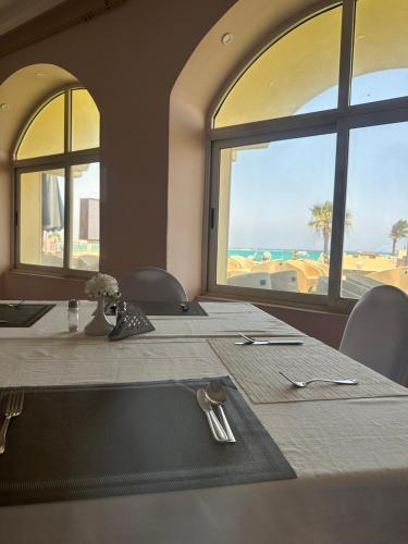 een eetkamer met een tafel en uitzicht op de oceaan bij Aros Al Bahr Hotel in Marsa Matruh
